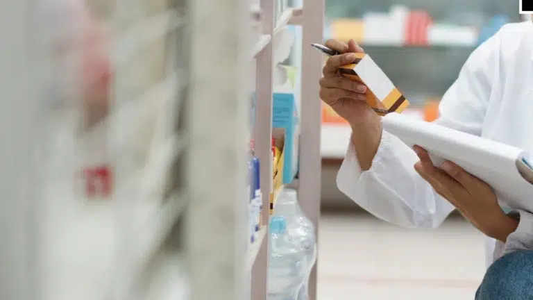 Uma pessoa verificando o preço de um medicamento que estava na prateleira.